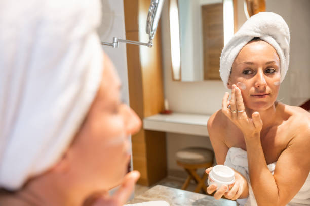istock Beautiful woman applying moisturizing creme on face after shower 1307715657