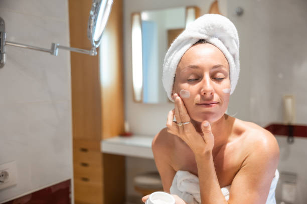istock Beautiful woman applying moisturizing creme on face after shower 1307715885