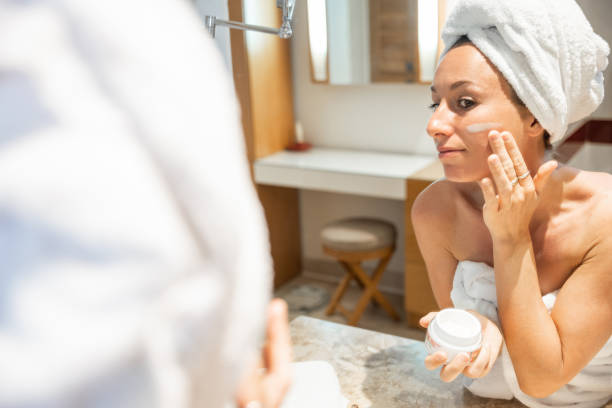 istock Beautiful woman applying moisturizing creme on face after shower 1307716583