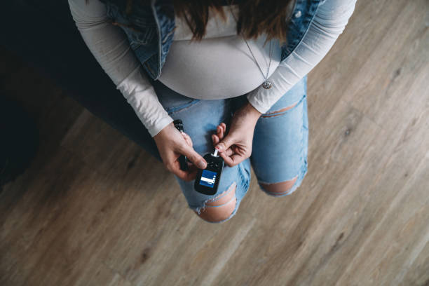 mujer embarazada analizando azúcar en la sangre en casa - diabetes human pregnancy women blood sugar test fotografías e imágenes de stock