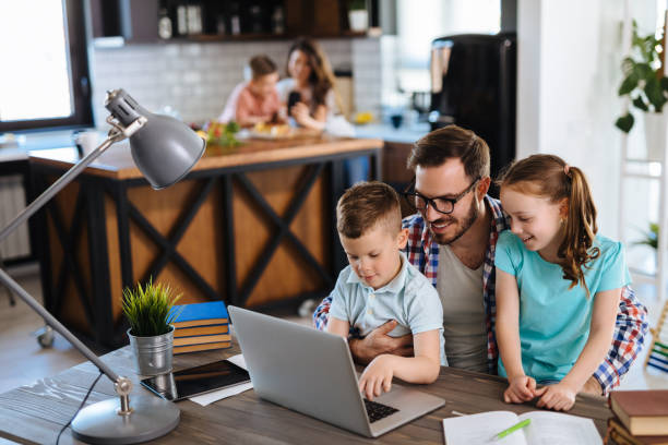istock Father with daughter and son on his lap using laptop at home 1307719165