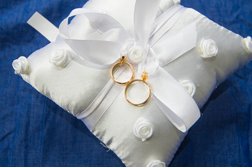 wedding rings on a white and soft pillow with beautiful and fragrant flowers, a symbol of love forever