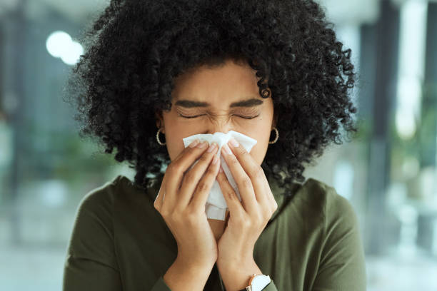 My immune system isn't what it needs to be Shot of a young businesswoman blowing her nose while working in a modern office sneezing stock pictures, royalty-free photos & images