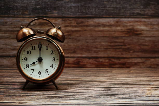 istock Vintage alarm clock with space copy on wooden background 1307723334