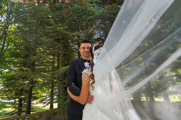 Groom and bride holding hands outdoors. Looking at each other. Wedding day. 30s.
