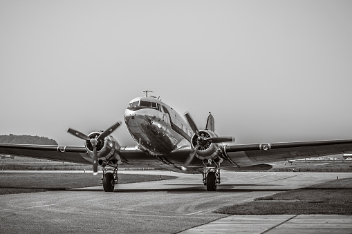 The image shows the nose of a Boeing B-17F WWII bomber.  The aircraft is parked on the ramp with a backdrop of a brooding, low overcast.  In black and white tones the photo presents a vintage, gritty quality like it was from the period.  The photo was taken at the Grant County International Airport in Moses Lake, WA.