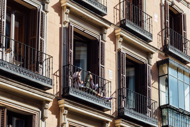 unidentified man sitting on balcony of old residential building in historic centre of madrid - madrid built structure house spain imagens e fotografias de stock