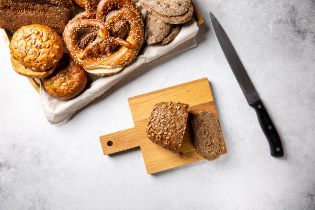istock Rye bread on cutting board, wooden tray with different kinds of bread on gray table. Top view, copy space, food background. 1307724736