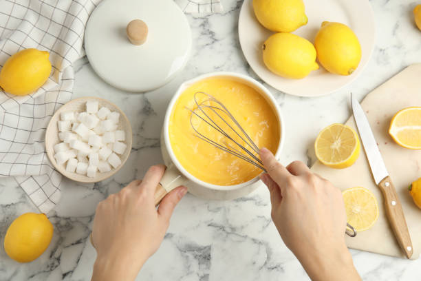 istock Woman cooking delicious lemon curd at white marble table, top view 1307726518