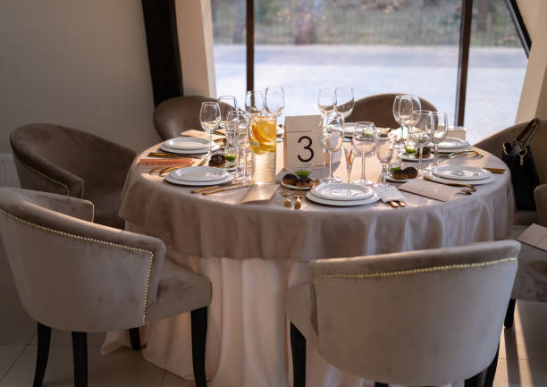 istock Chic and elegant, gold-plated cutlery and white plates, table setting with empty plates. On the table is an orange lemonade. The table opposite the window. 1307726805