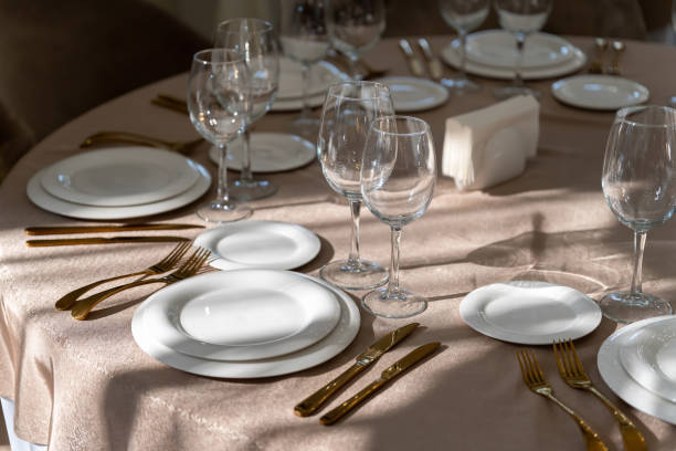chic and elegant, gold-plated cutlery and white plates, table setting with empty plates. beautiful rays of the sun from the window. - gold plated imagens e fotografias de stock