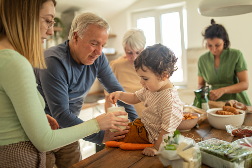 Multi-generation family enjoying time together while preparing breakfast together in kitchen