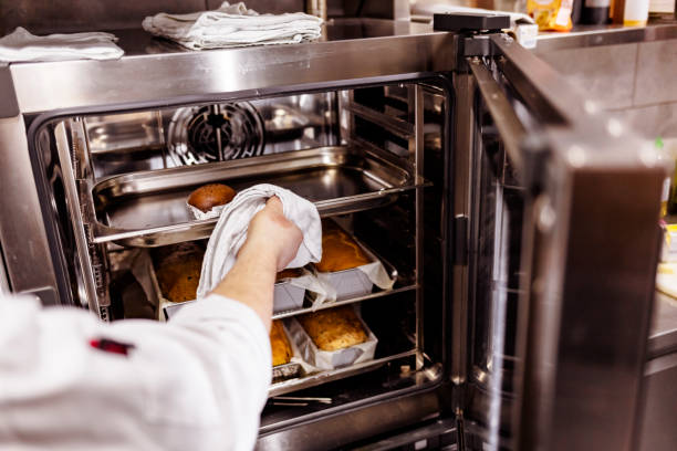 istock Baker's hand putting food into oven at restaurant kitchen 1307727009