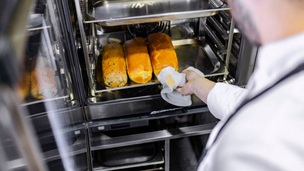istock Male baker taking fresh bread out of the oven 1307727742