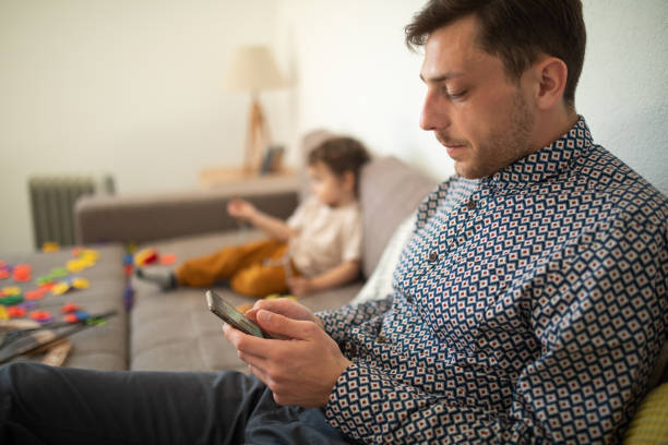 istock Young man sitting on sofa and using smartphone at home 1307727769