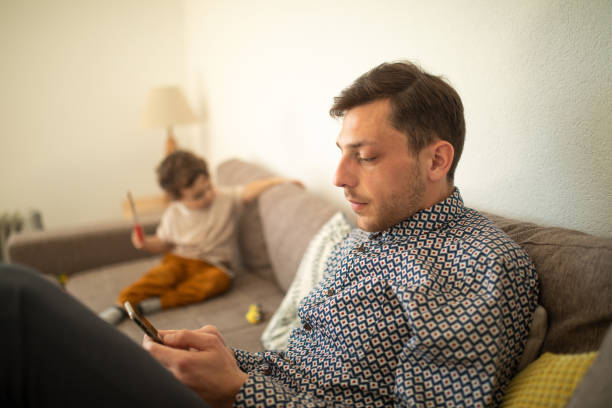 istock Young man sitting on sofa and using smartphone at home 1307727837