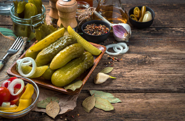 istock Pickled cucumbers, garlic and bay leaf on a wooden background 1307728132