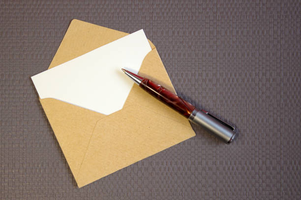 istock Simple small envelope with space for writing on grey background with a pen Narrow focus line, shallow depth of field 1307728713