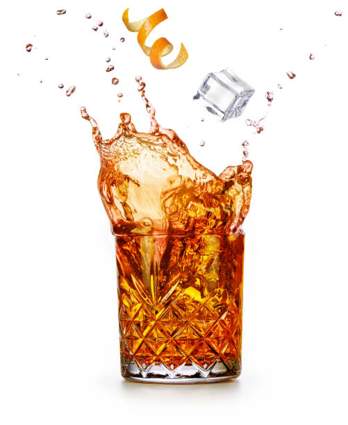 Alcoholic drink splashing on white background Orange zest and ice cube falling into a splashing drink. Godfather or old fashioned cocktail isolated on white background. vermouth stock pictures, royalty-free photos & images