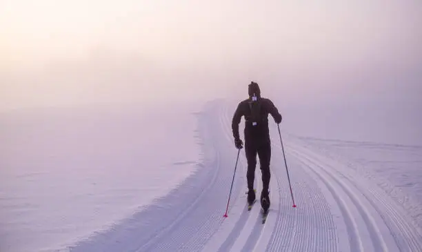 Man cross-country skiing in open, dreamy landscape in Norway.