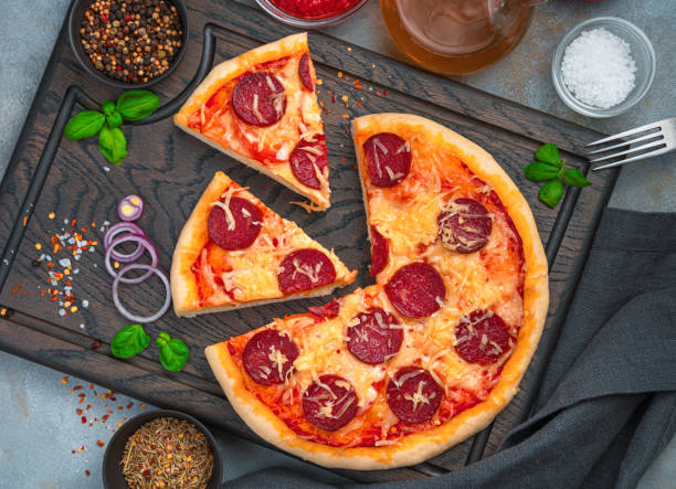 istock Sliced pizza on a board with onions and basil on a gray background 1307730467