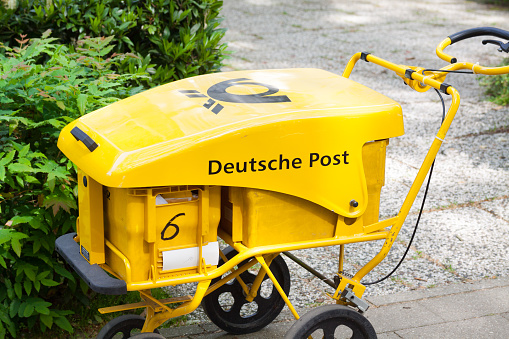 Pushcart of german mail service Deutsche Post standing on sidewalk