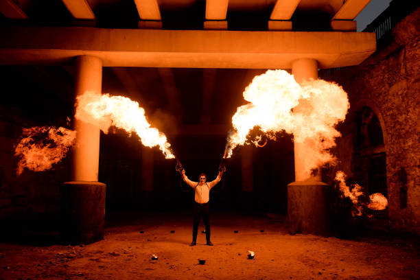 halloween man in costume with flamethrower in his hands. devil makeup on face - flamethrower imagens e fotografias de stock