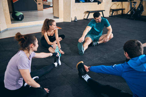 istock Flexible women and men performing the seated forward bend 1307733842