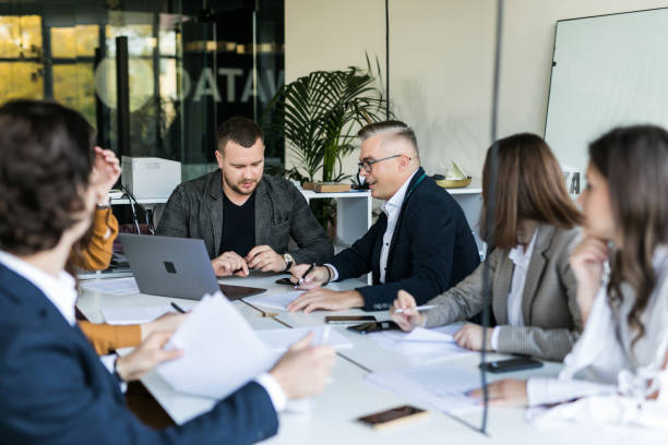 istock Business people showing team work while working in board room in office interior. People helping one of their colleague to finish new business plan. Business concept. Team work. 1307734089