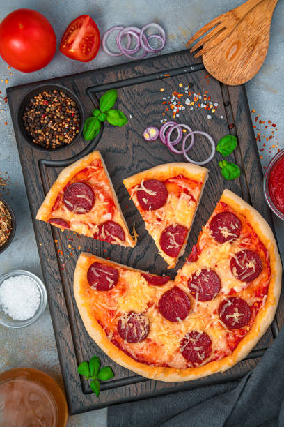 istock Pizza with basil, cheese and salami on a cutting board on a gray background 1307734177