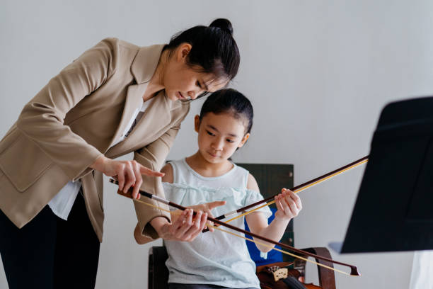 kleines mädchen mit geigenunterricht mit musiklehrer - practicing music violin women stock-fotos und bilder