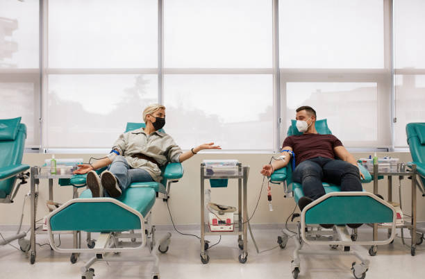 Couple Donating Blood Together Young couple donating blood together in blood bank. blood bank stock pictures, royalty-free photos & images