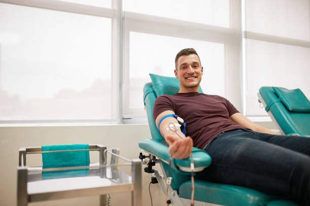 jonge mannelijke donor die bloed schenkt - bloedbank stockfoto's en -beelden