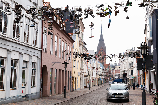 Flensburg, Germany - February 10, 2017: A lot of sporty shoes hang on wires, street view of Flensburg. Ordinary people walk the street