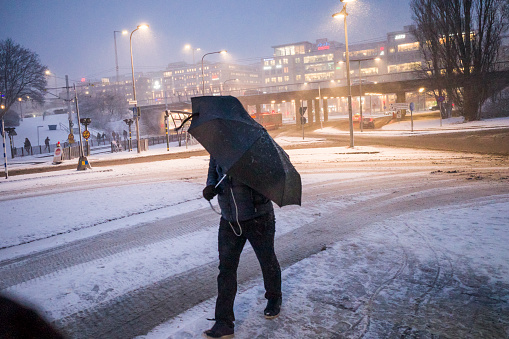 Stockholm, Sweden  March 12, 2021 A man walks in Liljeholmen with an umbrella in strong storm winds.
