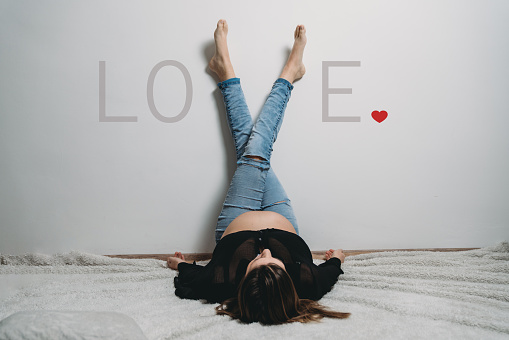 Conceptual shot of a pregnant woman forming the letter V of love with her legs. She's waiting her baby.