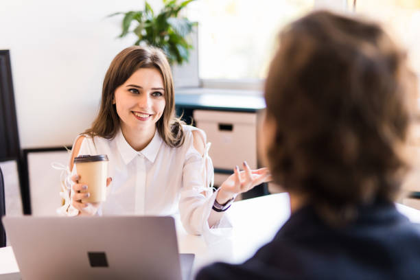 istock Business couple is using a laptop, discussing affairs, drinking coffee and smiling while working in the office 1307740823