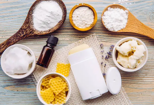 Photo of Making homemade deodorant stick with all natural ingredients concept. Blue wooden background. Ingredients: arrowroot powder, baking soda, beeswax, shea butter, essential oil, cornstarch, coconut oil.