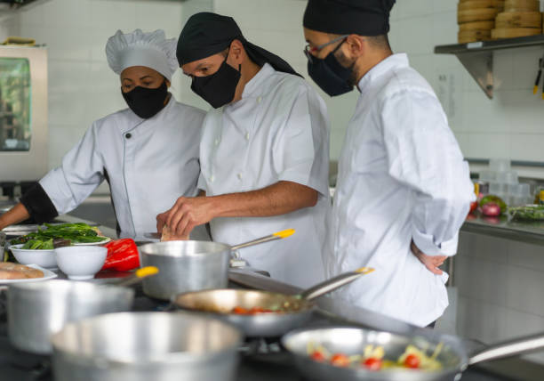 istock Chefs wearing facemasks while working together in a commercial kitchen during the pandemic 1307746899