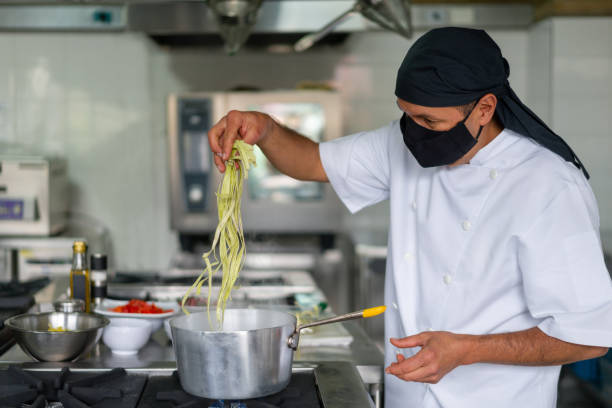 istock Cook working in a kitchen wearing a facemask during the pandemic 1307746932