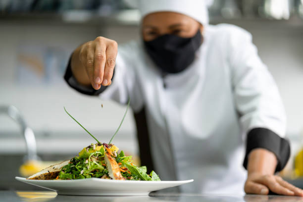 Chef wearing a facemask while decorating a plate in her kitchen during the pandemic