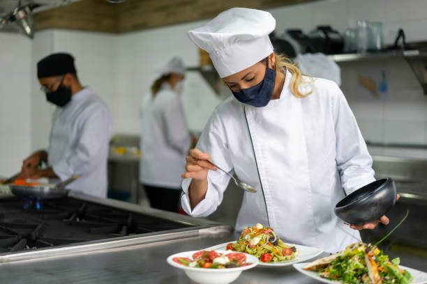istock Chef wearing a facemask while decorating a plate in her kitchen during the pandemic 1307746953
