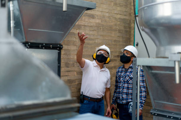 ingénieurs utilisant des masques de visage tout en faisant une inspection sur des conduits d’air à une usine - preventative maintenance photos et images de collection
