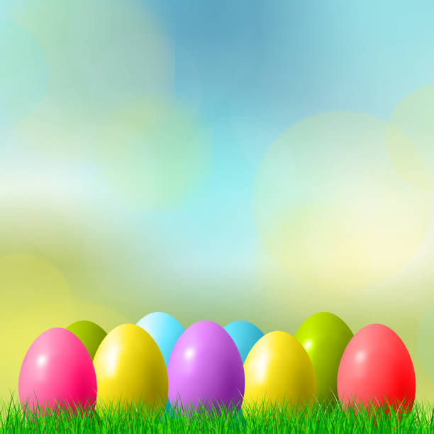 istock Abstract Easter bokeh background with colorful eggs lying on the grass against the sky background - illustration 1307747318