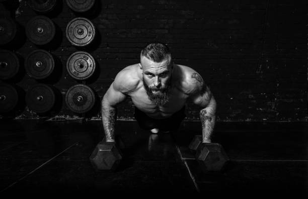 istock Young active sweaty strong fit muscular man with big muscles doing push ups on the dumbbells in the gym as hardcore cross workout training real people exercise 1307748308