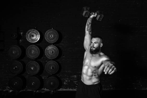 istock Young active sweaty strong fit muscular man with big muscles doing snatch or jerk workout with dumbbell weight in the gym as hardcore cross training real people exercising 1307748315
