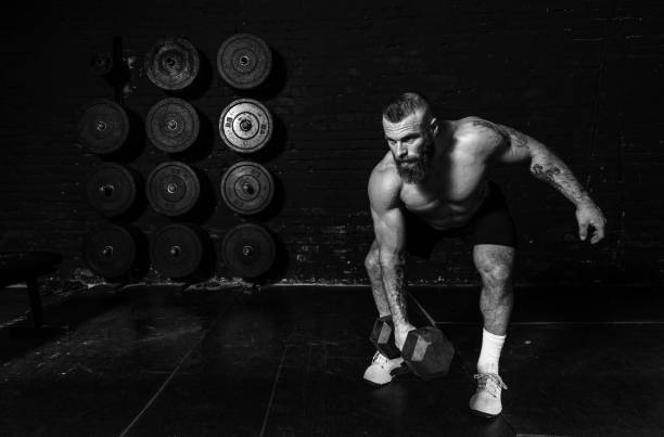 istock Young active sweaty strong fit muscular man with big muscles doing snatch or jerk workout with dumbbell weight in the gym as hardcore cross training real people exercising 1307748317