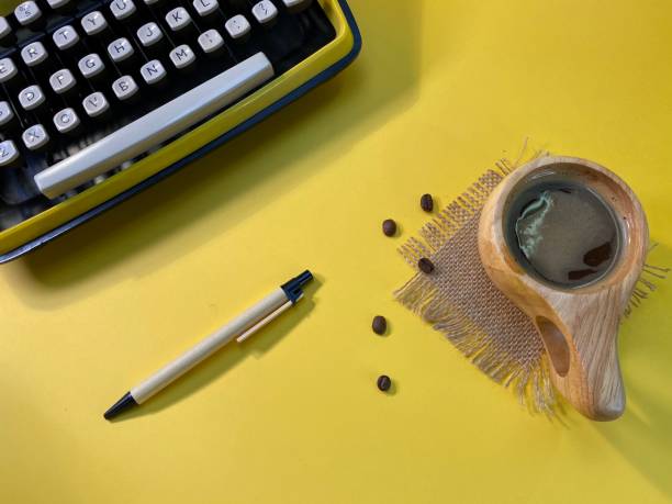 A typewriter is ready to work with a pen next to it