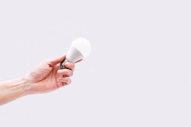 istock Energy saving light bulb. A man's hand holds a light bulb in his hands on a gray background. 1307750232
