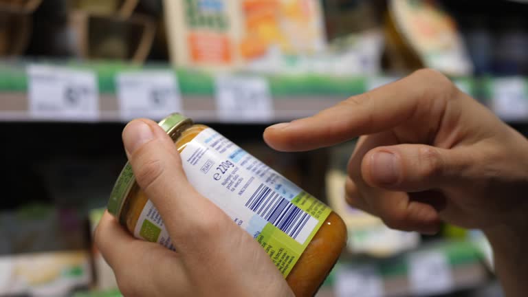 Woman reading the labels on a jar of children food. Conscious grocery shopping stock video 1307752184